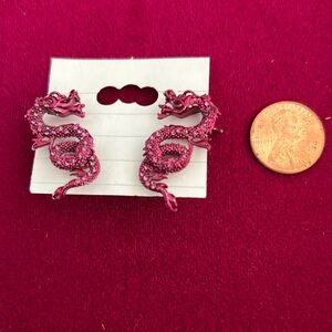 Magenta colored dragon earrings with an ear cuff that holds the dragon upright.
